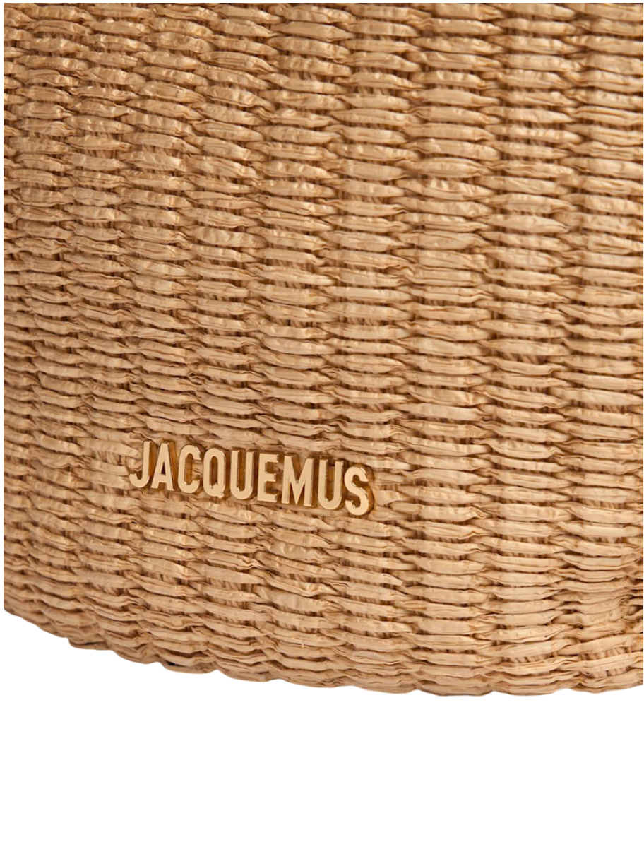 Close-up of Jacquemus logo on faux-raffia bucket bag with woven texture, emphasizing luxury craftsmanship.